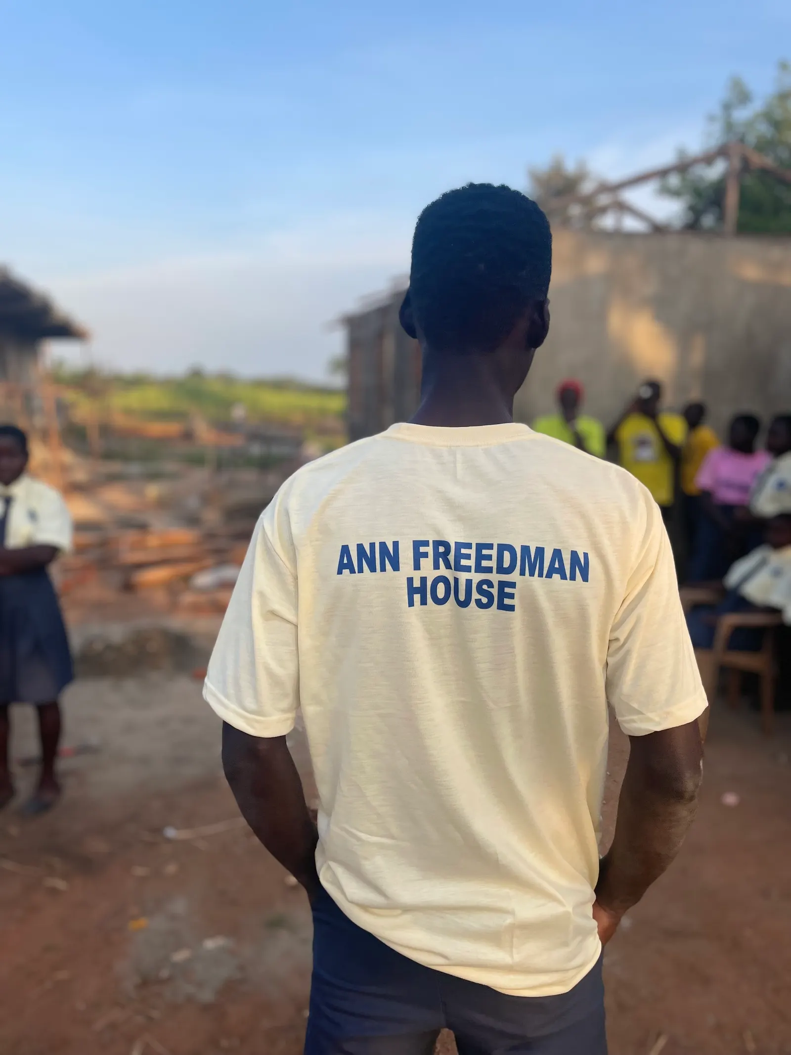 Student seen from behind wearing a cream Ann Freedman House t-shirt overlooking farmland