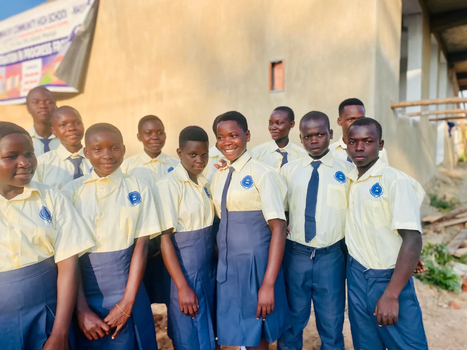 Students in uniform stand together outside the new classroom block
