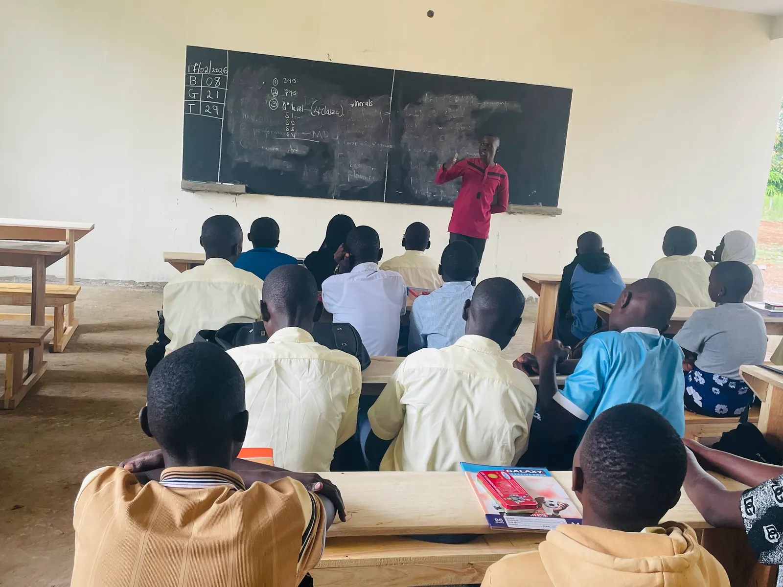 Students at wooden desks watching the blackboard