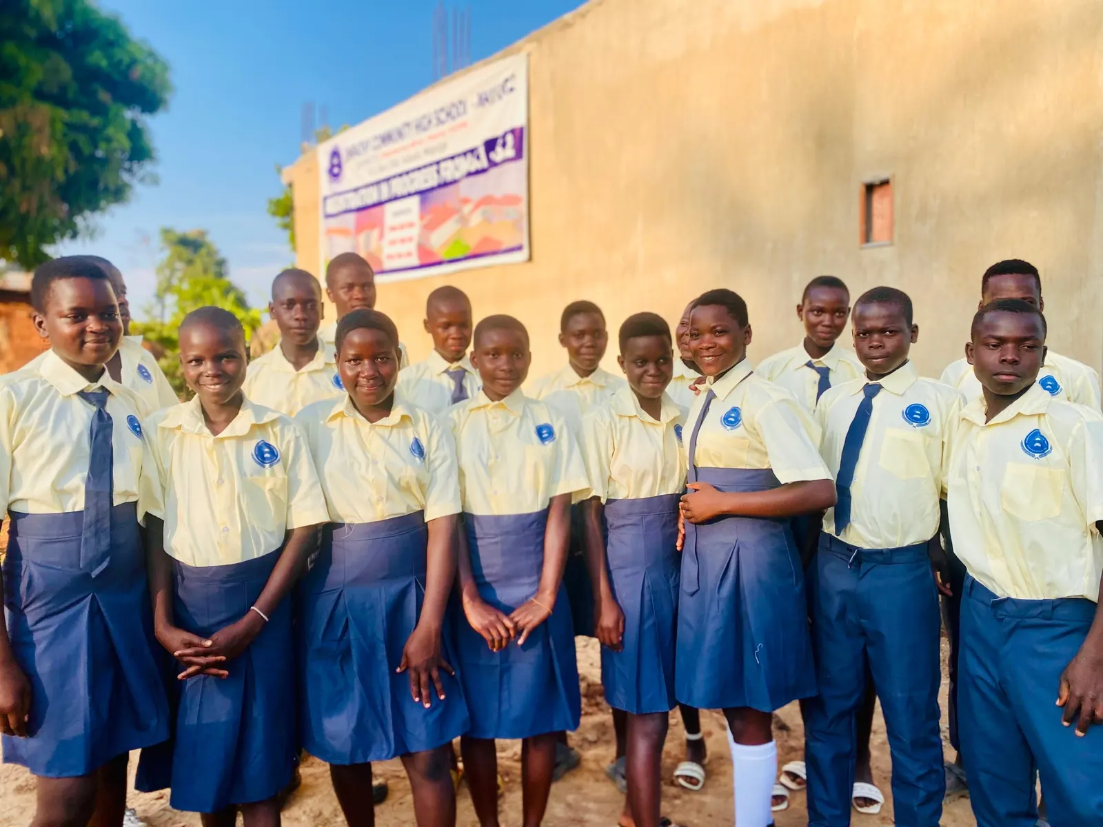 Students in uniform stand together in front of the school building
